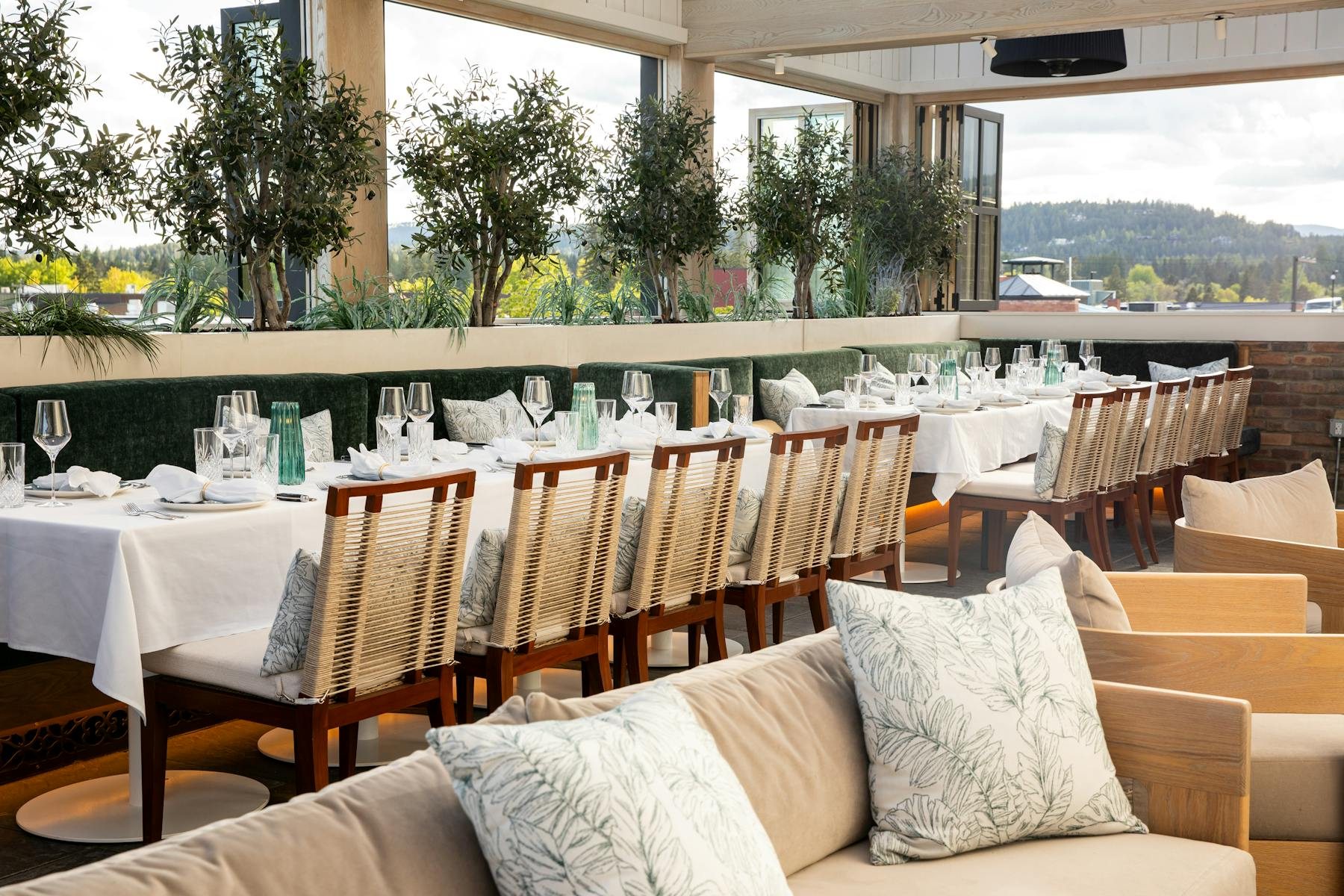 The covered Belvedere dining space with greenery and set tables