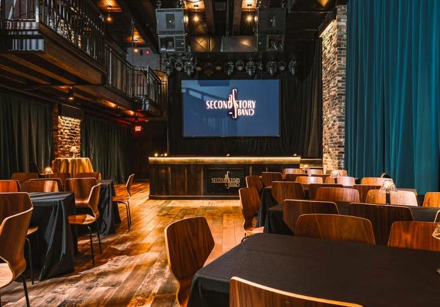 The Second Story room with tables, a stage and blue curtains